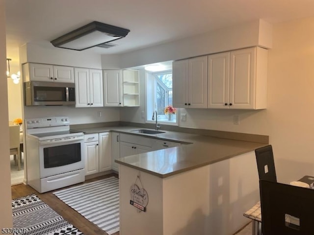 kitchen with electric stove, sink, kitchen peninsula, and white cabinets