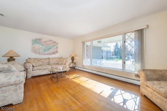 living room featuring a baseboard heating unit and hardwood / wood-style floors