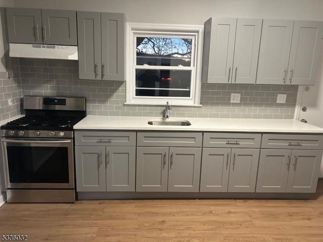 kitchen with stainless steel gas range, sink, light hardwood / wood-style flooring, and gray cabinetry