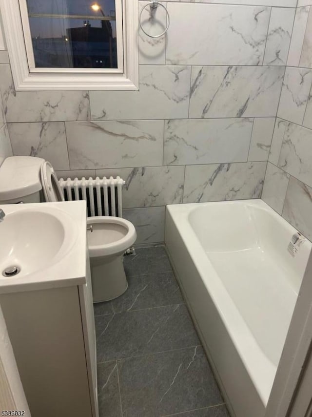 bathroom featuring vanity, a bath, radiator heating unit, and toilet