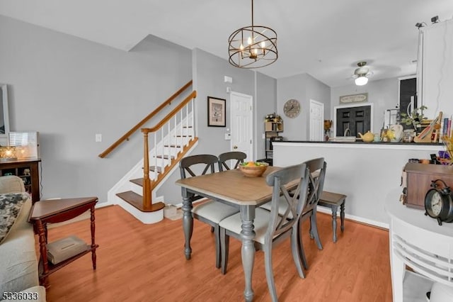 dining area with ceiling fan with notable chandelier and light hardwood / wood-style floors