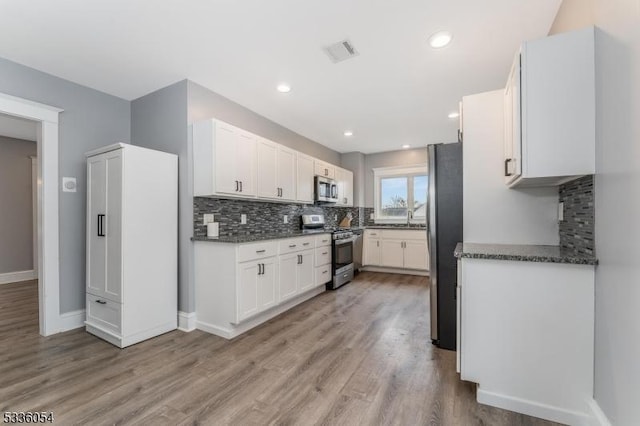 kitchen featuring decorative backsplash, light hardwood / wood-style flooring, stainless steel appliances, and white cabinets