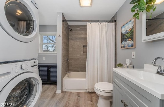 laundry room with sink, light wood-type flooring, and stacked washing maching and dryer