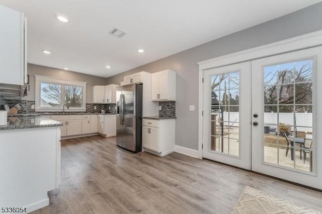 kitchen with white cabinetry, stainless steel refrigerator with ice dispenser, decorative backsplash, french doors, and light wood-type flooring