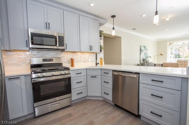 kitchen featuring sink, hanging light fixtures, ornamental molding, stainless steel appliances, and decorative backsplash