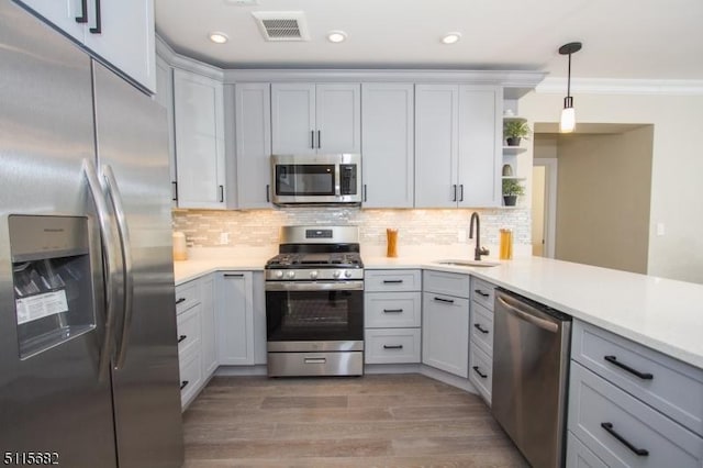 kitchen featuring sink, light wood-type flooring, pendant lighting, stainless steel appliances, and backsplash