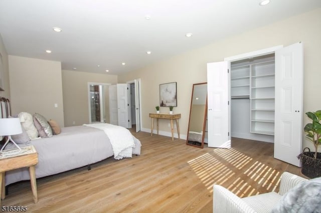 bedroom with a walk in closet and light hardwood / wood-style flooring