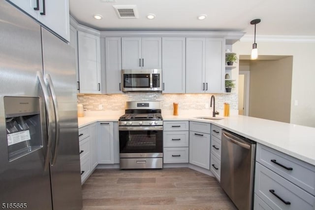 kitchen with sink, stainless steel appliances, tasteful backsplash, light hardwood / wood-style floors, and decorative light fixtures