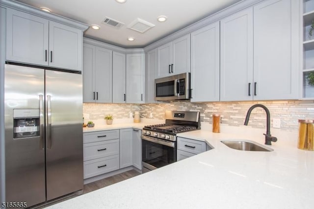 kitchen with sink, backsplash, light stone countertops, and appliances with stainless steel finishes