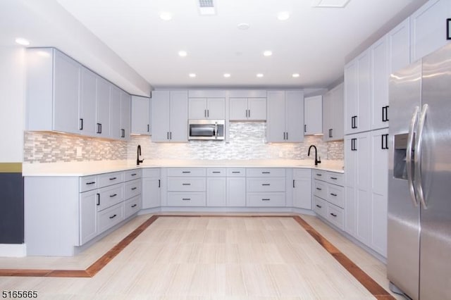 kitchen with tasteful backsplash, appliances with stainless steel finishes, and sink