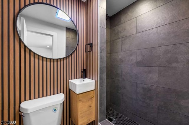 bathroom with vanity, tiled shower, and toilet