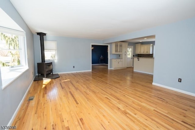 unfurnished living room featuring light wood-type flooring and a wood stove