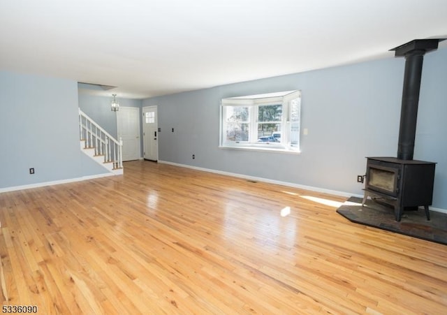 unfurnished living room with a wood stove and light hardwood / wood-style flooring