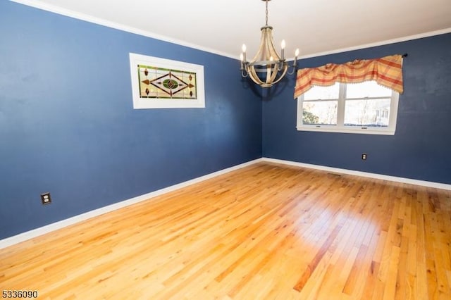 empty room featuring crown molding, hardwood / wood-style floors, and a notable chandelier