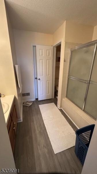 bathroom with hardwood / wood-style flooring, vanity, an enclosed shower, and a textured ceiling