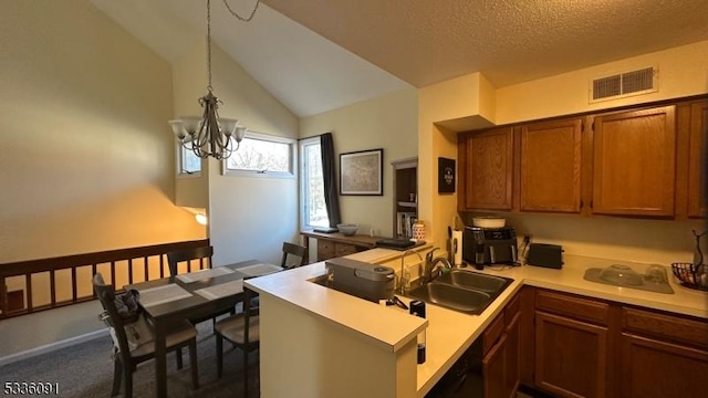 kitchen with vaulted ceiling, sink, hanging light fixtures, kitchen peninsula, and an inviting chandelier