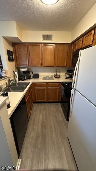 kitchen with dark hardwood / wood-style flooring, sink, a textured ceiling, and black appliances