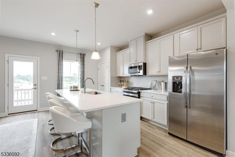 kitchen featuring stainless steel appliances, white cabinetry, sink, and a kitchen island with sink