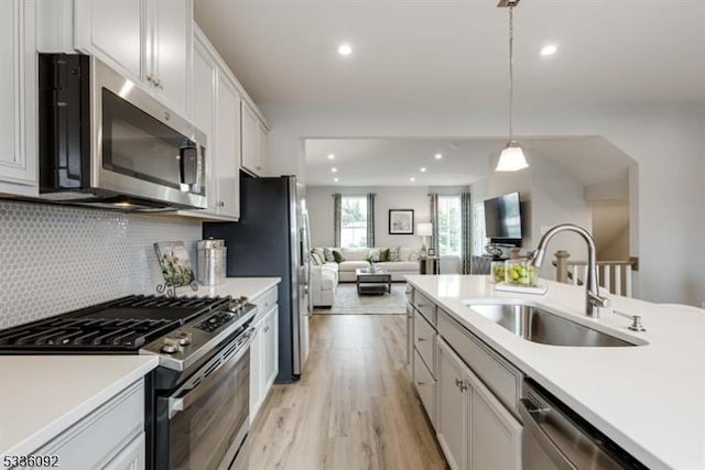 kitchen featuring sink, white cabinetry, appliances with stainless steel finishes, pendant lighting, and decorative backsplash