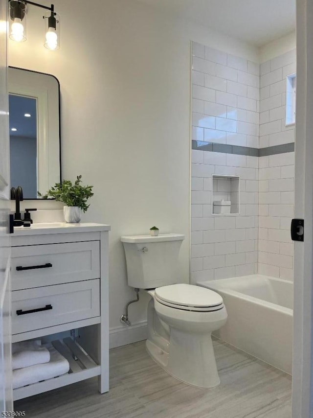 full bathroom with vanity, tiled shower / bath combo, and toilet