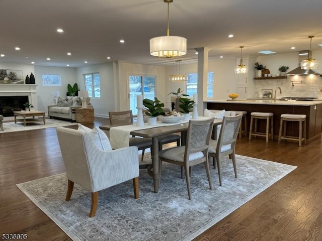 dining room featuring sink, decorative columns, and dark hardwood / wood-style floors