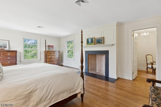 bedroom with multiple windows, a notable chandelier, crown molding, and light hardwood / wood-style floors