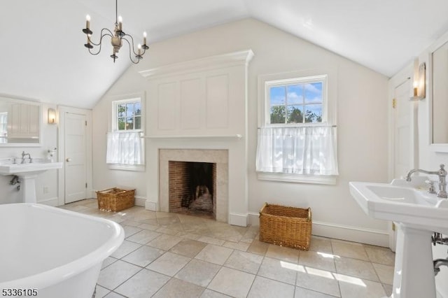 bathroom featuring lofted ceiling, sink, a tub to relax in, tile patterned flooring, and a notable chandelier