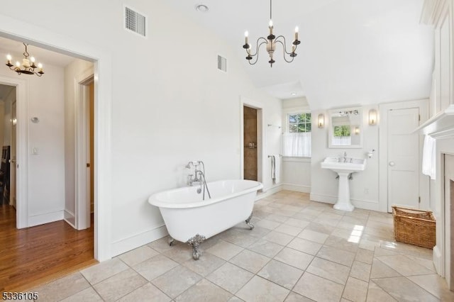 bathroom with tile patterned flooring, vaulted ceiling, a bathtub, and a chandelier