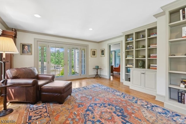 living area with ornamental molding and light hardwood / wood-style floors