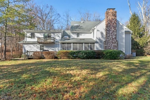 rear view of house with a sunroom, a deck, and a lawn