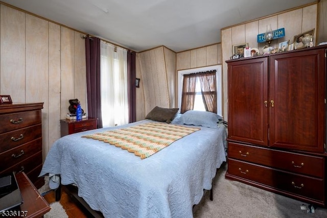 bedroom featuring light carpet and wooden walls