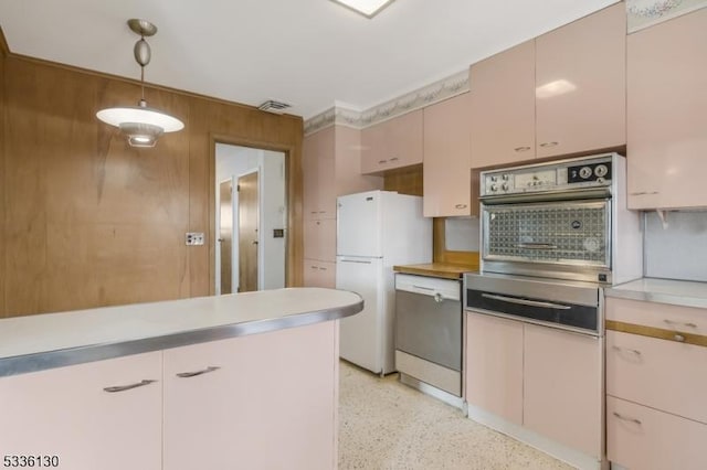 kitchen with white refrigerator, stainless steel oven, decorative light fixtures, and wooden walls