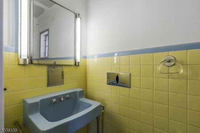 bathroom featuring sink and tile walls