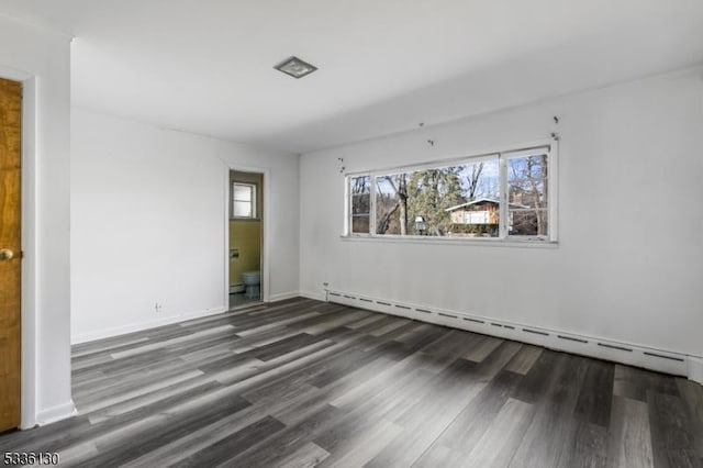 spare room with a baseboard heating unit and dark hardwood / wood-style flooring