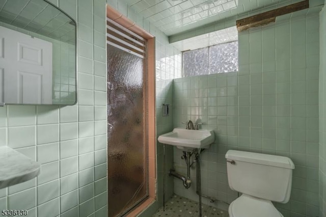 bathroom featuring walk in shower, toilet, sink, and tile walls