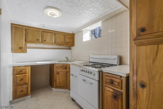 kitchen with sink, white gas stove, and tile walls