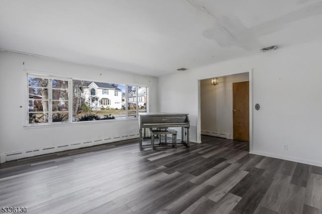 empty room with dark hardwood / wood-style floors and a baseboard heating unit