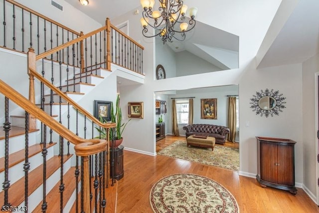 entrance foyer featuring high vaulted ceiling, hardwood / wood-style floors, and a notable chandelier