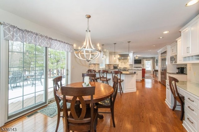 dining room with an inviting chandelier, built in desk, and hardwood / wood-style floors