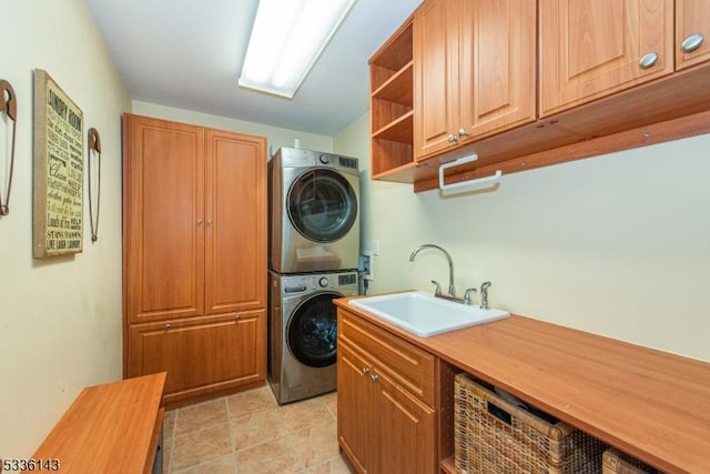 laundry area with sink, light tile patterned floors, cabinets, and stacked washer / dryer