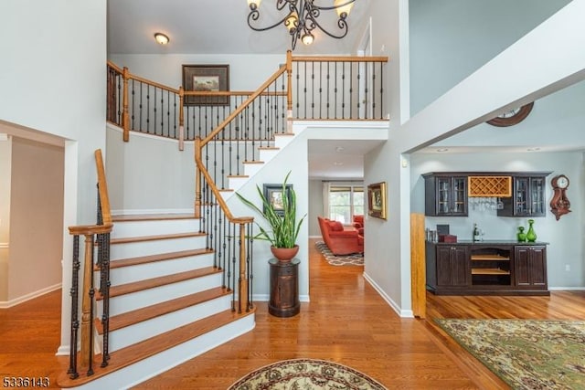 entryway featuring hardwood / wood-style flooring, a high ceiling, bar, and a chandelier