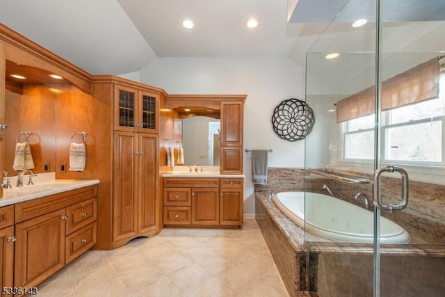 bathroom with a relaxing tiled tub, vanity, tile patterned flooring, and vaulted ceiling