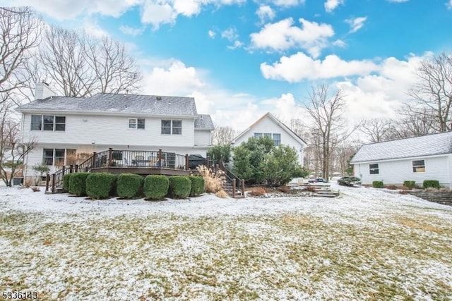 snow covered back of property featuring a wooden deck