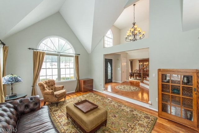 living room featuring a chandelier, high vaulted ceiling, and light hardwood / wood-style flooring