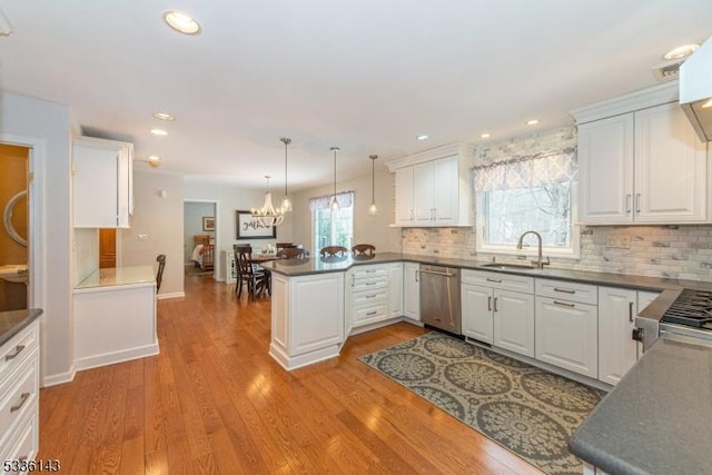 kitchen with pendant lighting, sink, white cabinets, stainless steel dishwasher, and kitchen peninsula