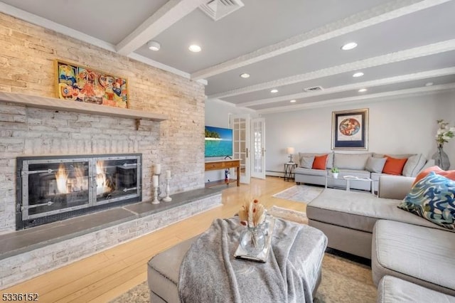 living room featuring a baseboard heating unit, beam ceiling, a fireplace, and light hardwood / wood-style floors