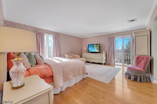 bedroom featuring crown molding, multiple windows, light hardwood / wood-style flooring, and access to outside