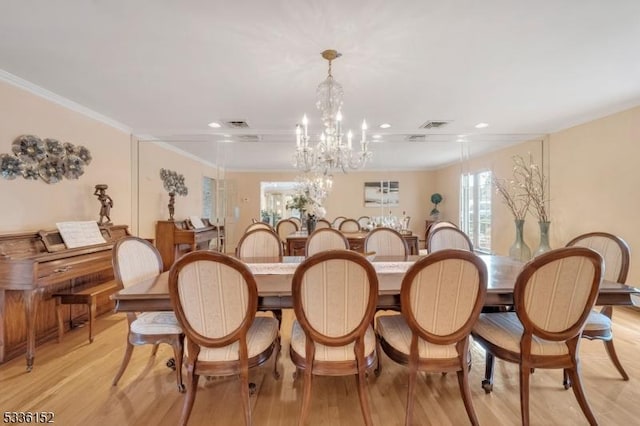 dining space with an inviting chandelier, ornamental molding, and light hardwood / wood-style floors