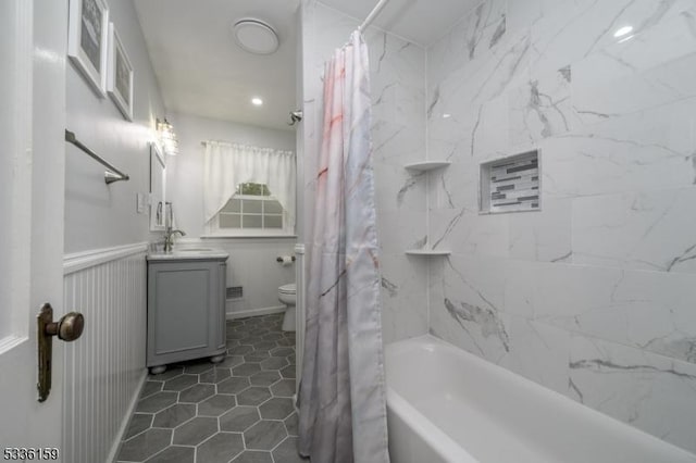 full bathroom featuring tile patterned flooring, a wainscoted wall, toilet, shower / tub combo with curtain, and vanity