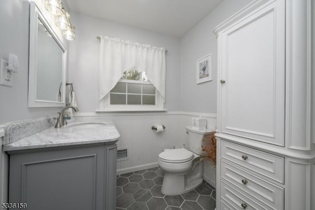 bathroom with visible vents, a wainscoted wall, toilet, tile patterned floors, and vanity